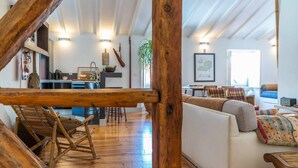 A spacious living area with a wooden ceiling, a sofa, a dining table, and a kitchen in the background. - Stylish 2BR Loft w/ Views • Av. Liberdade & Metro (Lisbon)
