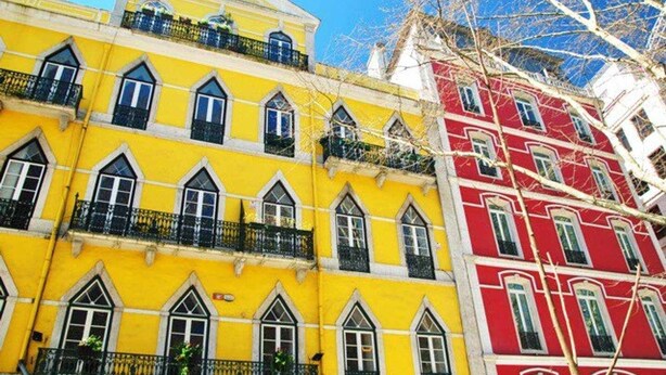 A row of colorful buildings with distinct yellow and red facades, featuring traditional window designs and balconies. - Stylish 2BR Loft w/ Views • Av. Liberdade & Metro (Lisbon)