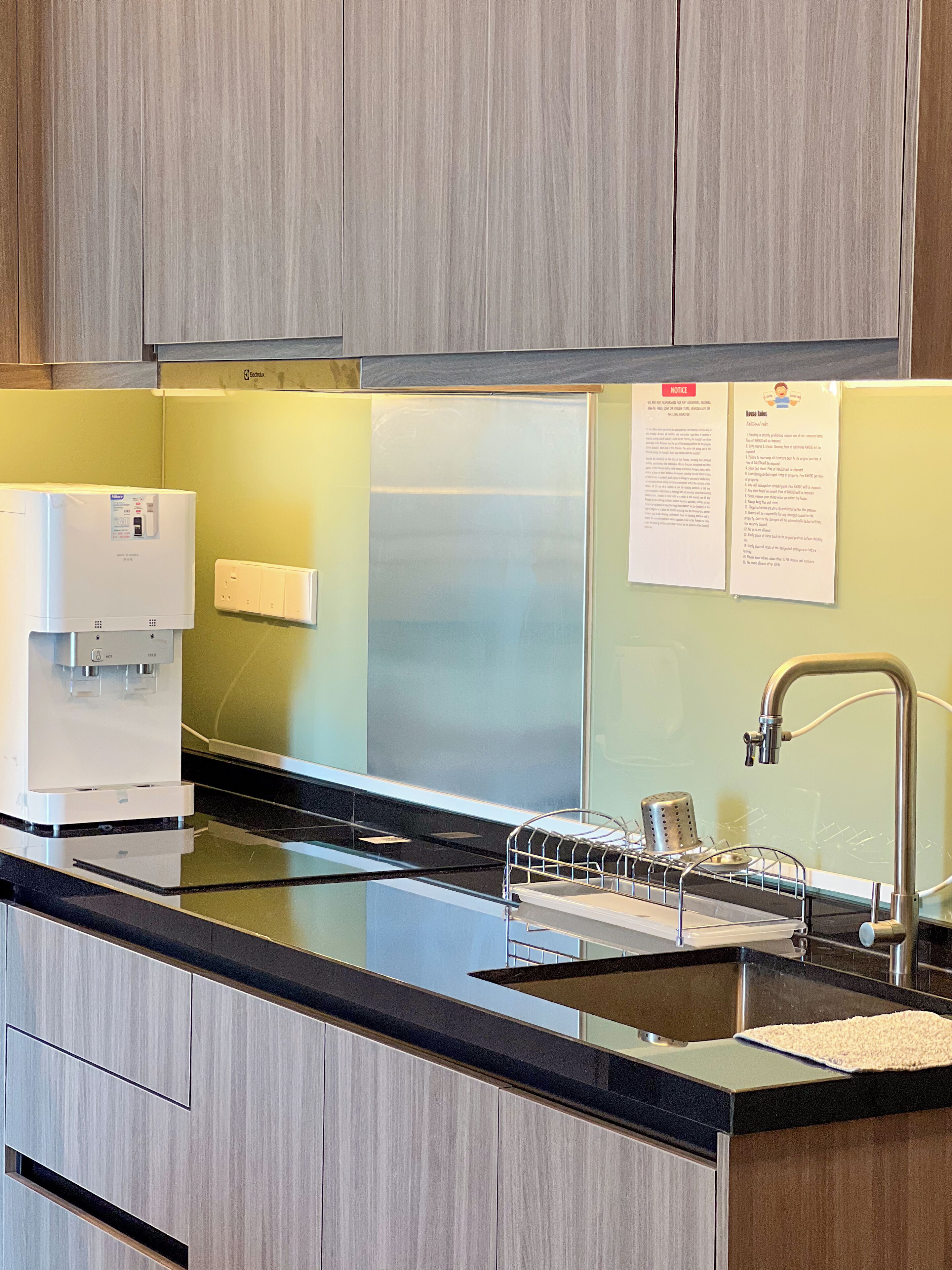 Una cocina moderna con cafetera integrada, pileta de acero inoxidable y dispensador de toallas de papel.