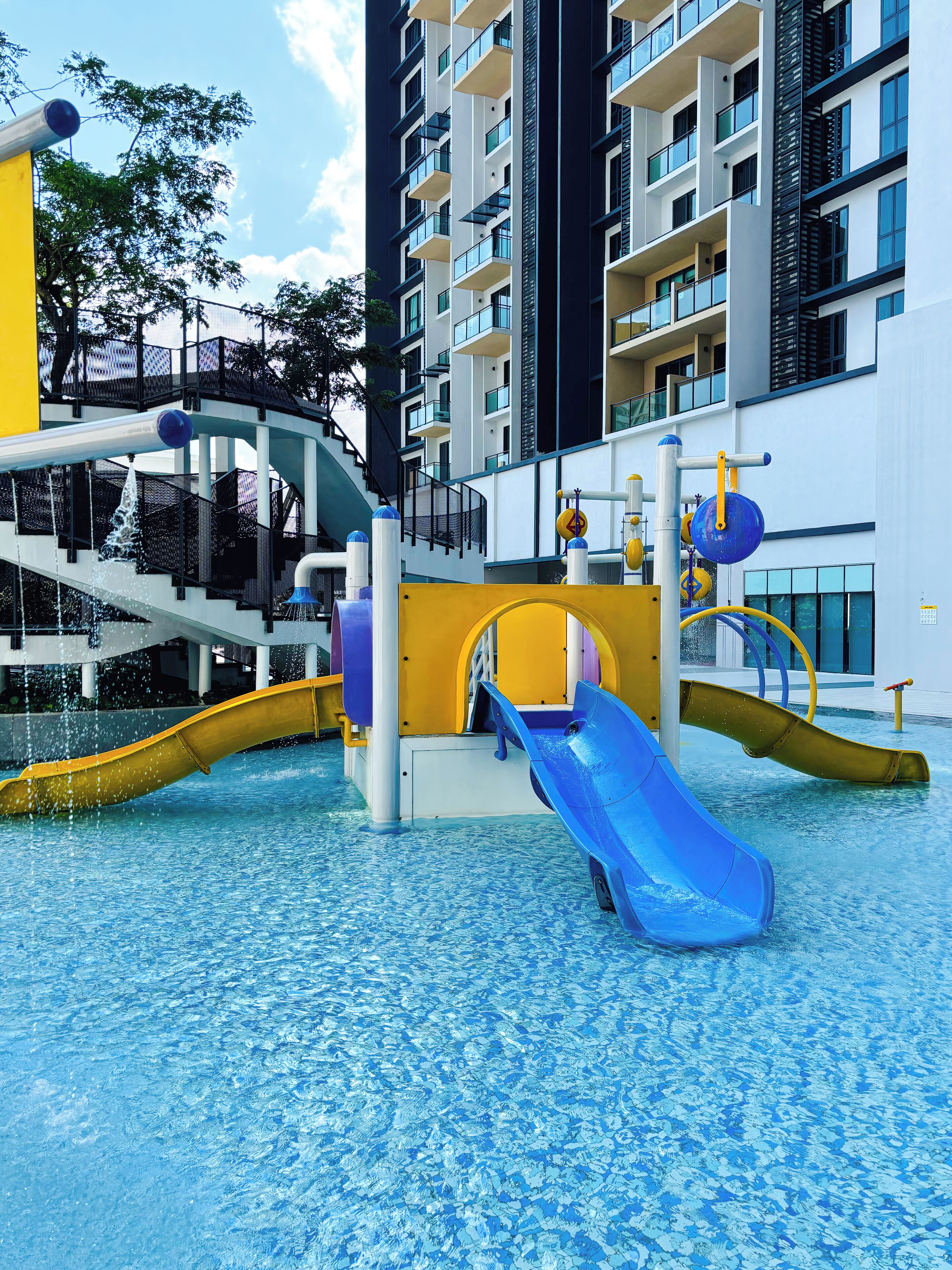 A water park with slides and water features, surrounded by a high-rise building.