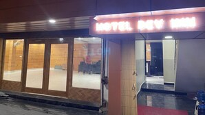 Een hotelentree met een neonreclame, houten lambrisering en een zichtbare binnenruimte met zitplaatsen.
