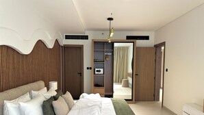 A modern bedroom with a large bed, a wardrobe, a mirror, and a ceiling light.