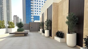 A modern outdoor area with a seating area, potted plants, and a view of high-rise buildings.