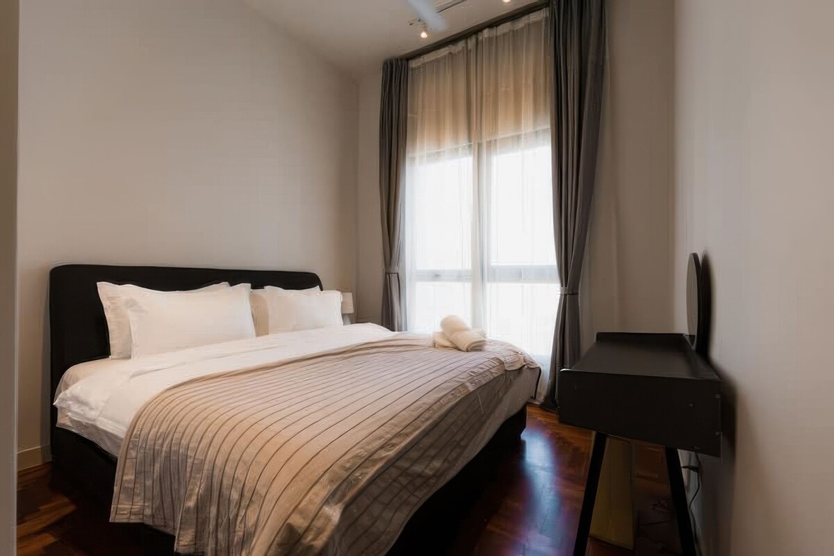 Une chambre à coucher avec un lit, une table de chevet et une fenêtre avec des rideaux.