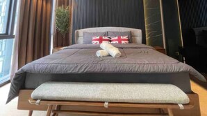 Ein modernes Schlafzimmer mit einem großen Bett, einem Nachttisch, einer Topfpflanze und Blick auf die Stadt durch große Fenster.