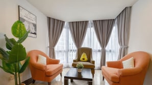 Ein Zimmer mit zwei orangefarbenen Sesseln, einem kleinen Tisch, einer Topfpflanze und einem Sessel mit gelbem Kissen.