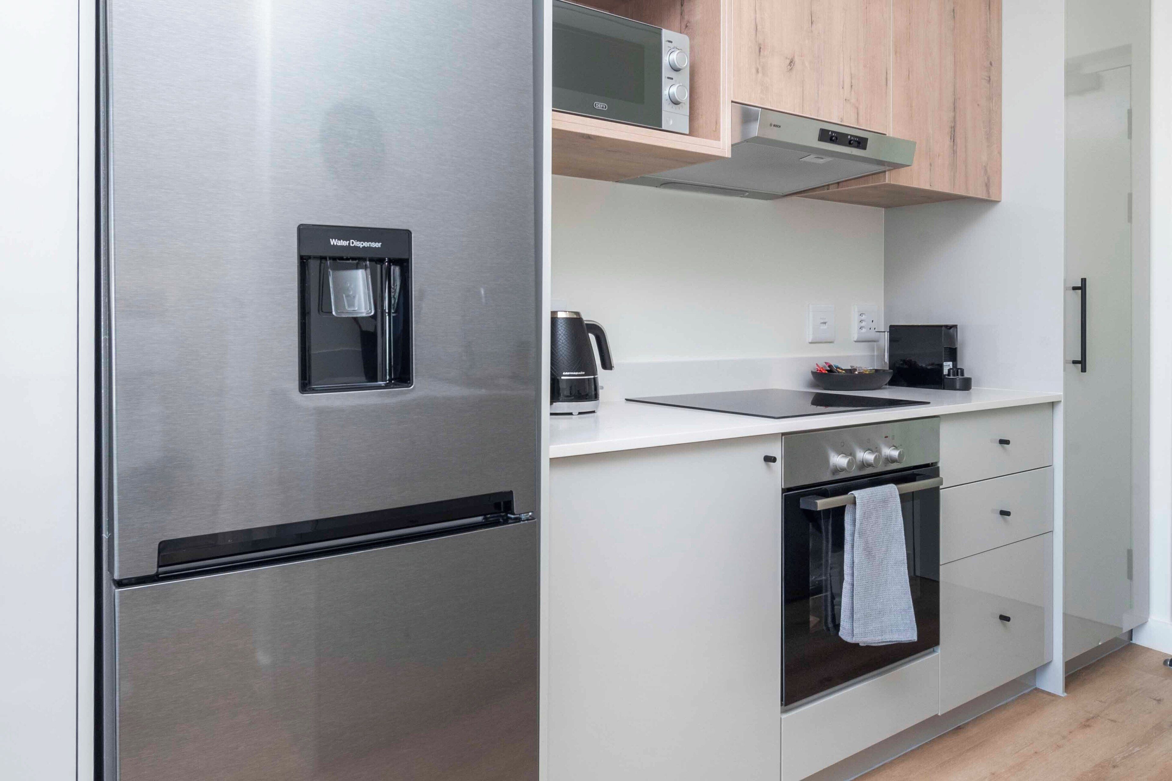 A modern kitchen with a stainless steel refrigerator, a microwave, a coffee maker, and a built-in oven.