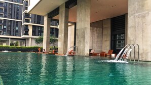 En swimmingpool med vandelementer og liggestole.