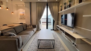 En moderne stue med sofa, sofabord, fjernsyn og reoler.