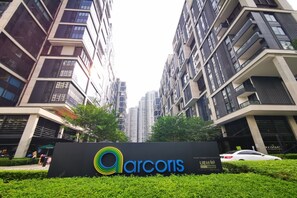 A modern high-rise building with a sign for 'Arcoris' in front.