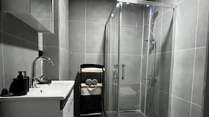 A modern bathroom with a glass-enclosed shower, a white sink, and a toilet. - LİGHTHOUSE SUİTE (Atakum)