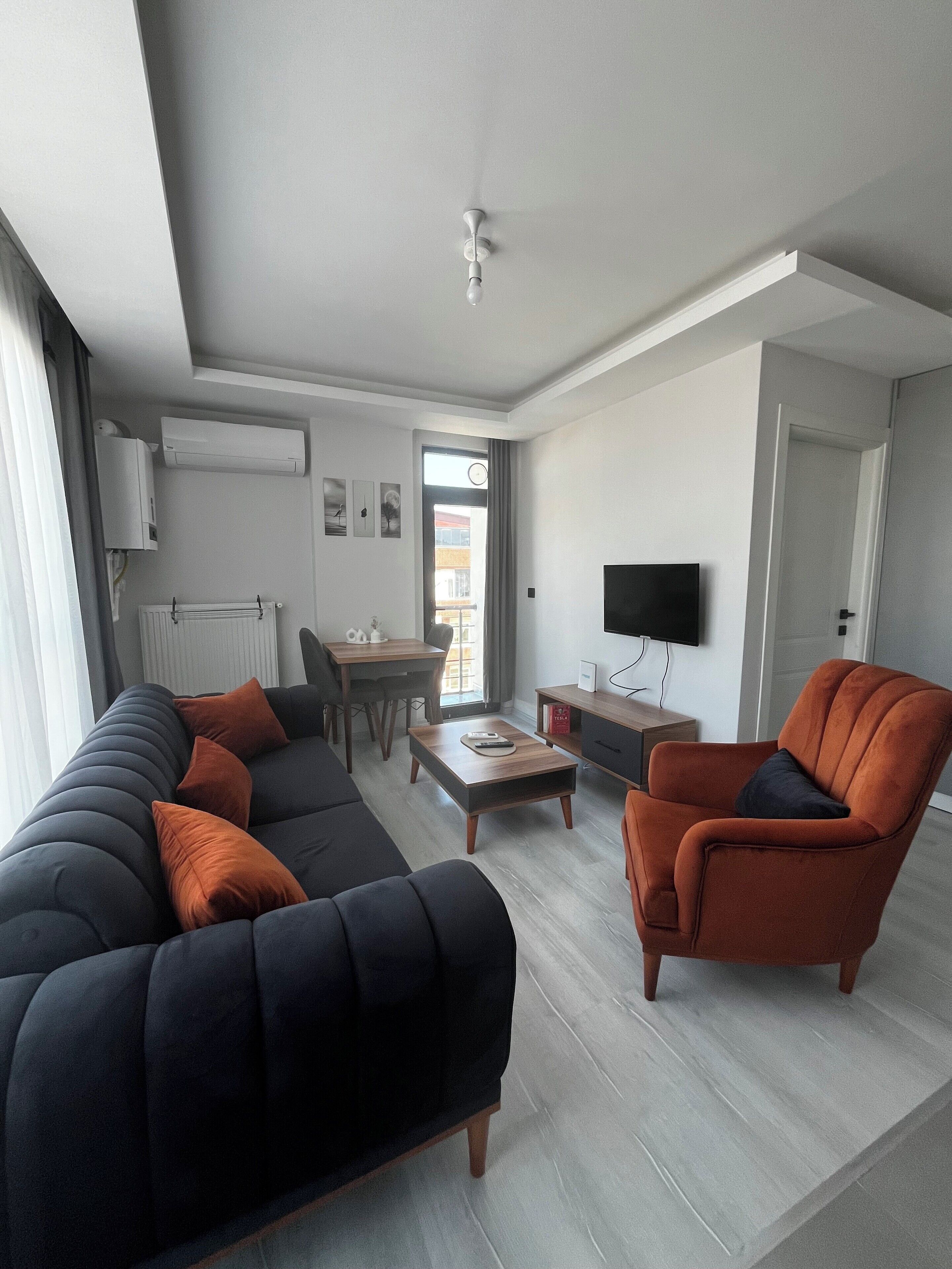 A modern living room with a sofa, armchair, coffee table, and a flat-screen TV.