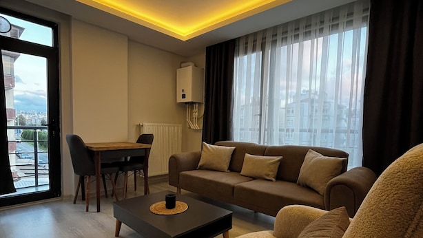 A modern living room with a sofa, coffee table, and dining area. - LİGHTHOUSE SUİTE (Atakum)