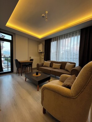 A modern living room with a sofa, coffee table, and dining area. - LİGHTHOUSE SUİTE (Atakum)