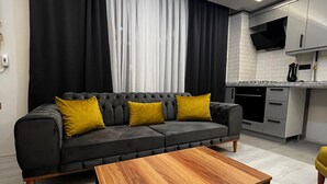 A modern living room with a dark grey sofa, yellow cushions, and a wooden coffee table. - LİGHTHOUSE SUİTE (Atakum)