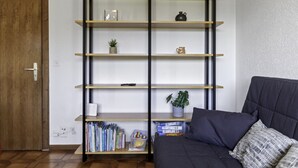 Een kamer met een boekenkast, een donkere bank en een houten deur.