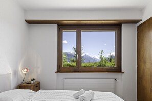 Una camera da letto con un'ampia finestra, un comodino con una lampada e un letto rifatto.
