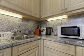 A kitchen with granite countertops, stainless steel sink, and wooden cabinets.