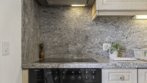 Een keuken met een granieten aanrecht, een ingebouwde vaatwasser en een fornuis.