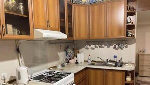 A kitchen with wooden cabinets, a stove, a sink, and various kitchen items. - Your apartment next to Yerevan State University (Martuni)