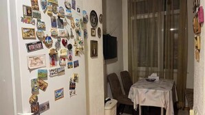 A room with a refrigerator covered in magnets and photos, a dining table with chairs, and a television on the wall. - Your apartment next to Yerevan State University (Martuni)