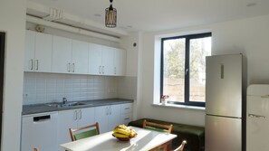 Una cuina amb armaris blancs, forn encastrat, finestra amb vistes i taula de menjador amb cadires.