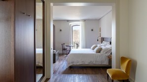 A hotel room with a bed, a chair, a small table, and a view of a courtyard. - Palazzina Gentile (Bari)