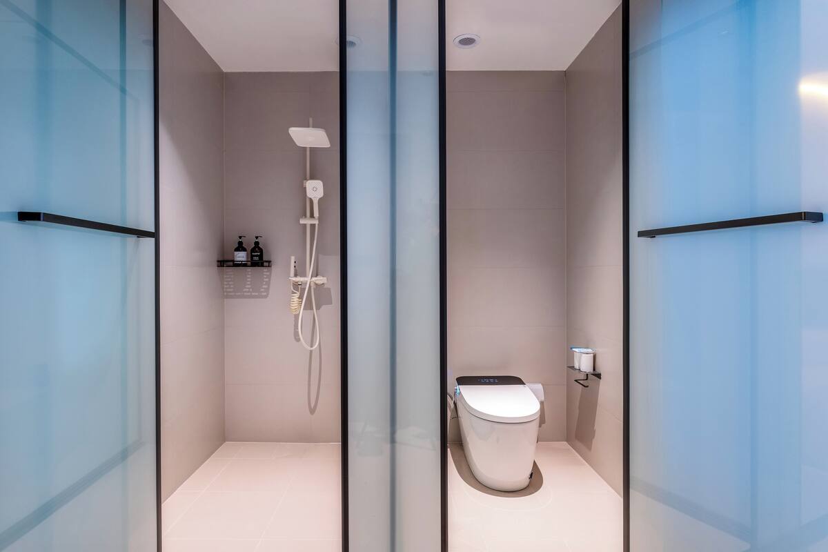 Une salle de bain moderne avec une paroi en verre, une douche et des toilettes.
