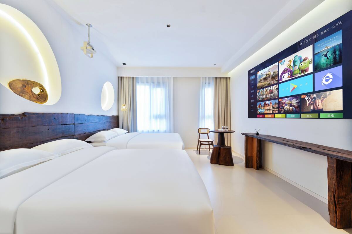 Une chambre d’hôtel avec deux lits, un mur dédié à la télévision et une petite table.