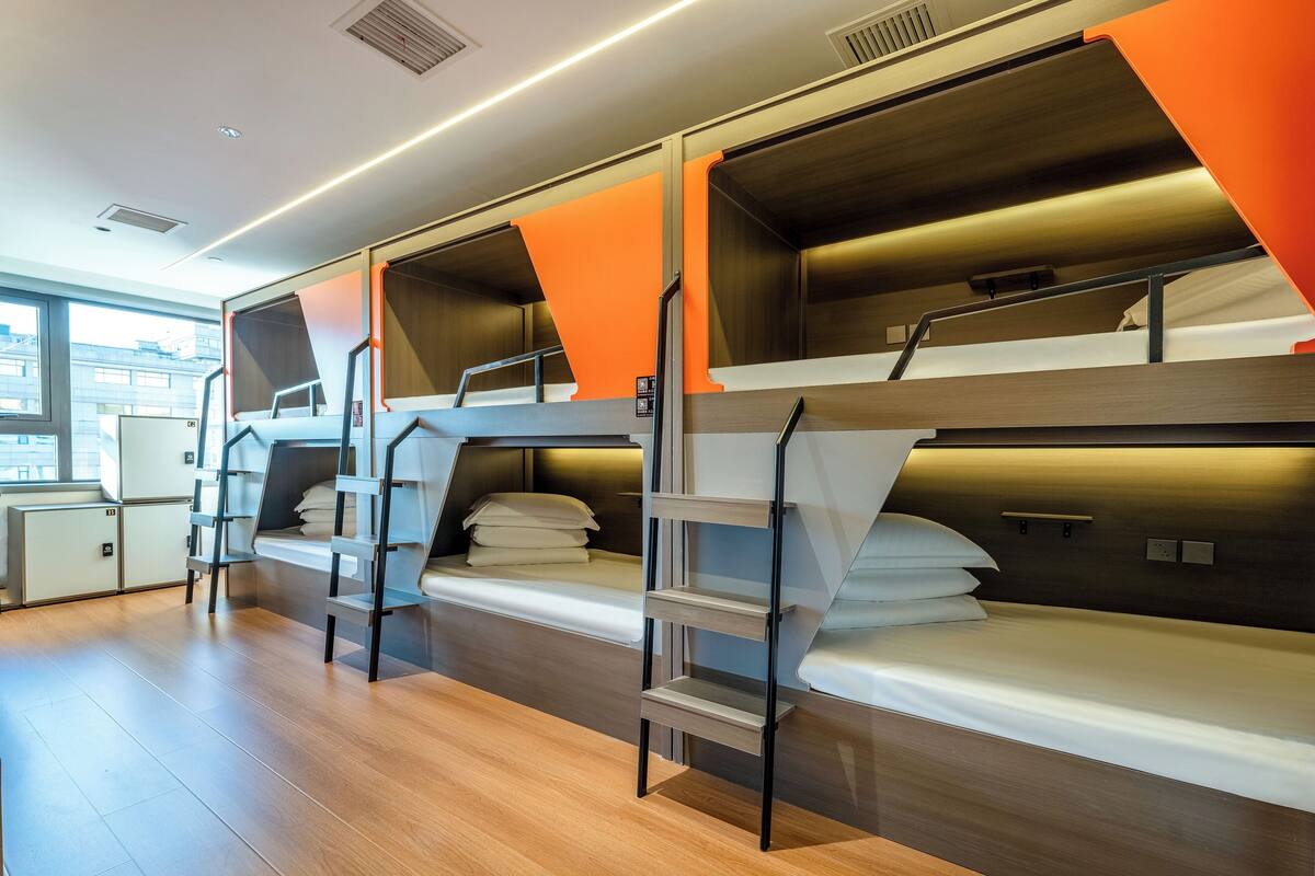 Une chambre d’hôtel moderne avec des lits superposés, un plancher en bois et une vue sur la ville.