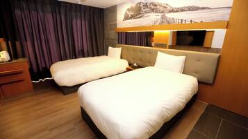 A hotel room with two beds, a wooden desk, a flat-screen TV, and a large window with curtains.