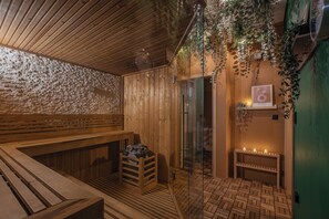 A wooden sauna with benches, a glass door, and a shelf with candles. - Hotel Slovan (Jesenik)