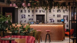 Un espace bar avec un mur décoré de motifs, des tableaux encadrés et des tabourets de bar.