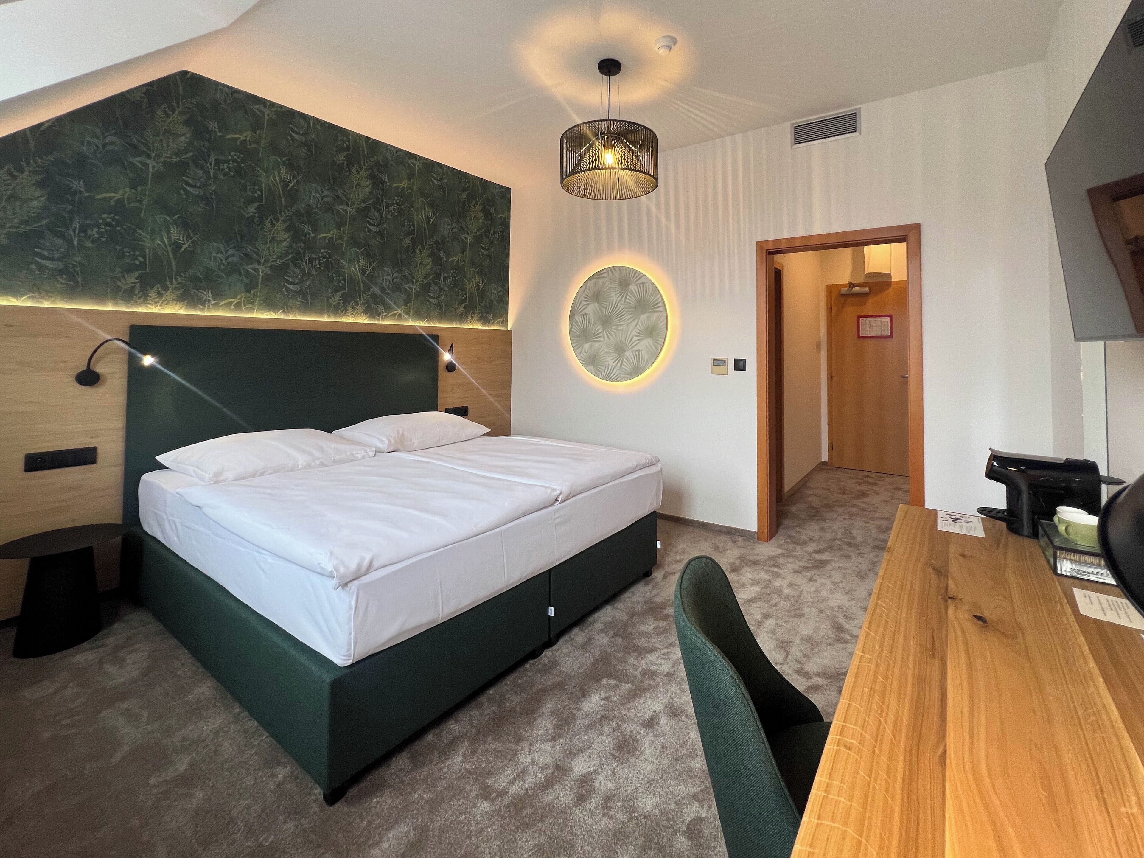 A modern hotel room with a large bed, a desk, and a round wall decoration.