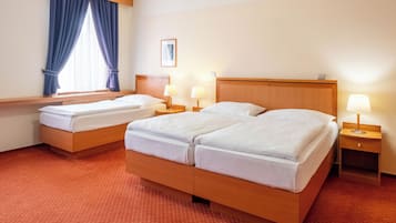 A hotel room with two beds, a window with curtains, bedside lamps, and a framed picture on the wall.