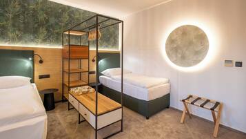 A hotel room with a bunk bed, a bedside table, a wall-mounted lamp, and a circular light fixture.