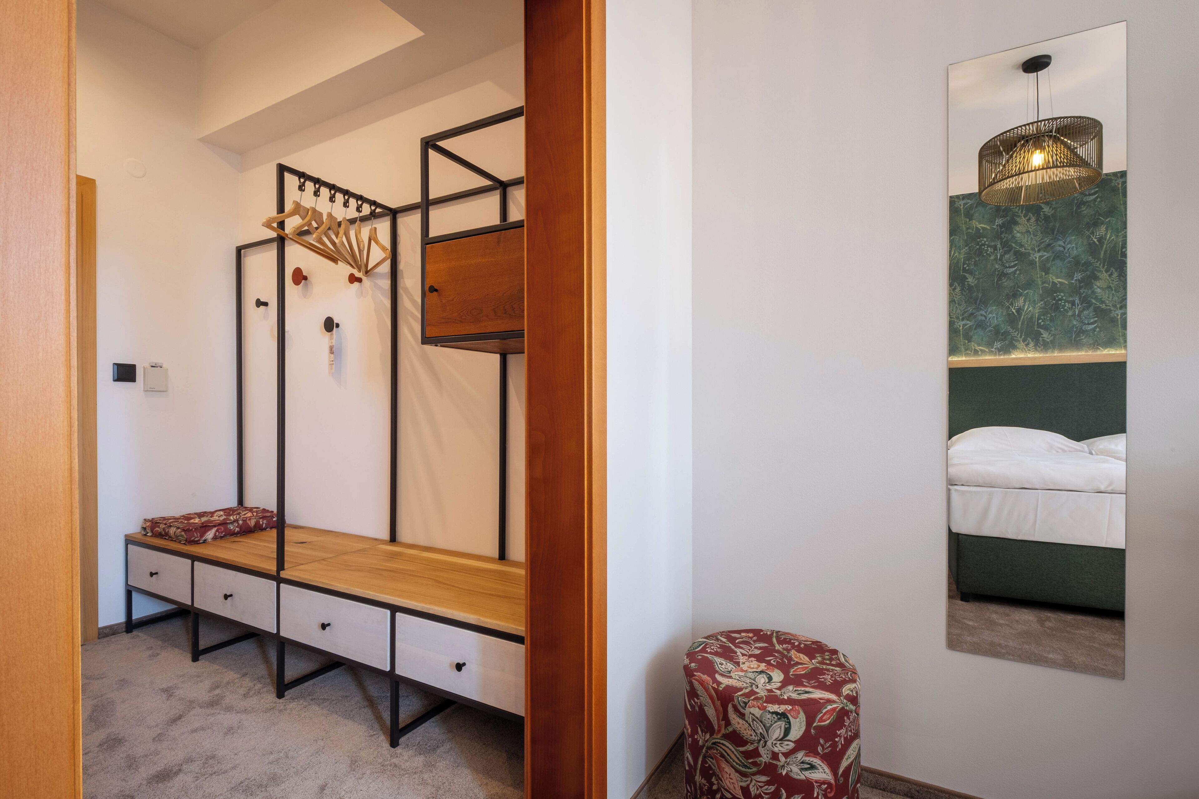 A bedroom with a wooden bed frame, a wall-mounted shelf with hanging items, and a framed picture of a bed.