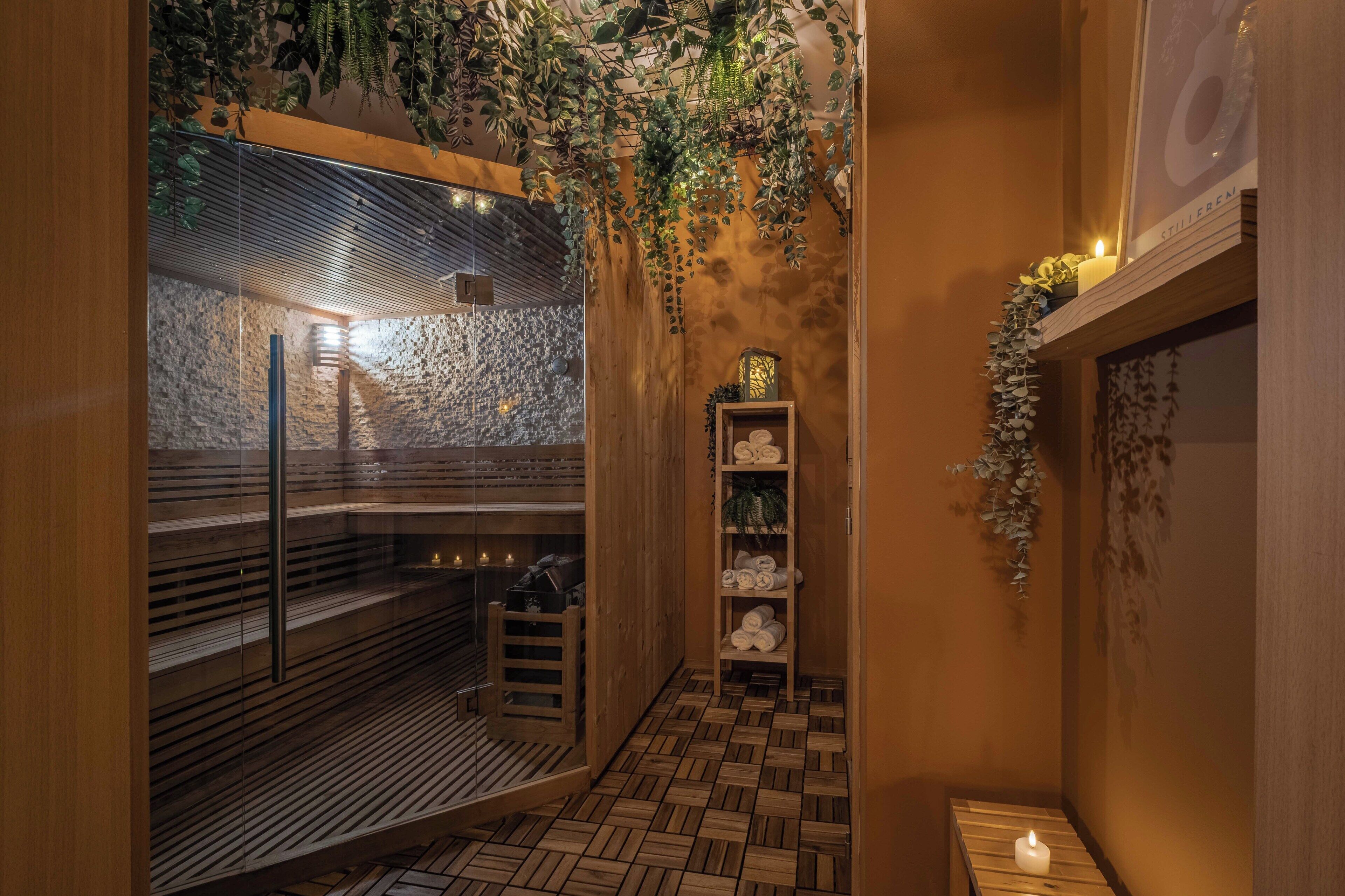 A modern spa with a stone wall, wooden benches, and a shelf with towels.