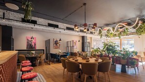 Un espace repas moderne avec une table en bois, plusieurs chaises et un bar avec des tabourets.