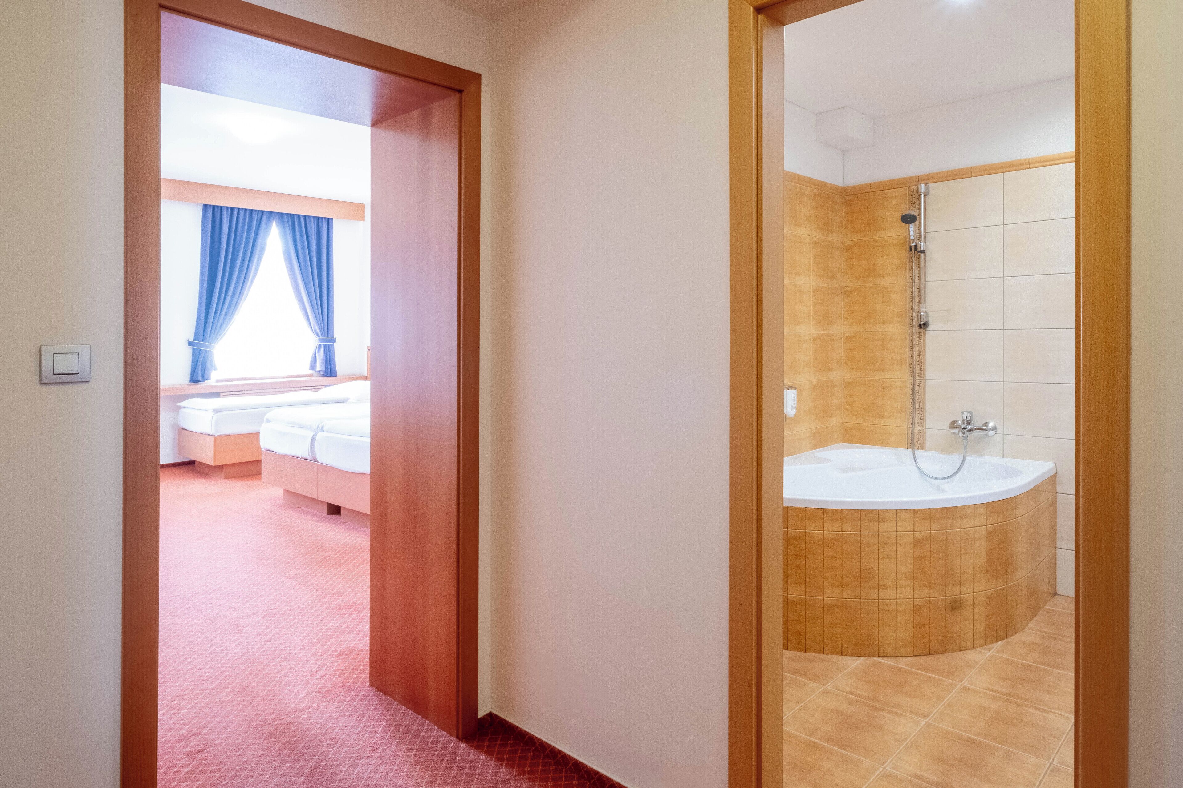 Habitación de hotel con una cama grande, baño con bañera y vistas al exterior.