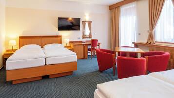 A hotel room with a bed, a desk, a chair, and a TV.