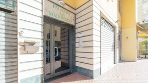 L’entrée du Palazzo La Madonnina se distingue par une porte en verre, une boîte aux lettres et un sol recouvert de carreaux.
