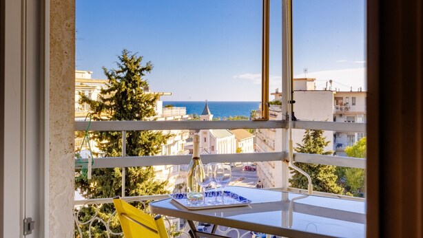 Un balcon avec une table, une chaise et une bouteille de vin.