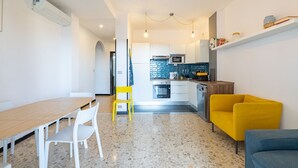 Une cuisine moderne avec des meubles blancs, un four à micro-ondes et une cuisinière. On y trouve également un coin repas avec une table et des chaises en bois.