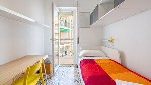 Une chambre à coucher de taille réduite, comprenant un lit, un bureau et une chaise.