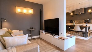A modern living room with a flat-screen TV, sofa, and dining area. - L'appartement Charlot L (Paris)