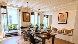 A dining area with a wooden table, chairs, and pendant lighting. - L'appartement Charlot L (Paris)