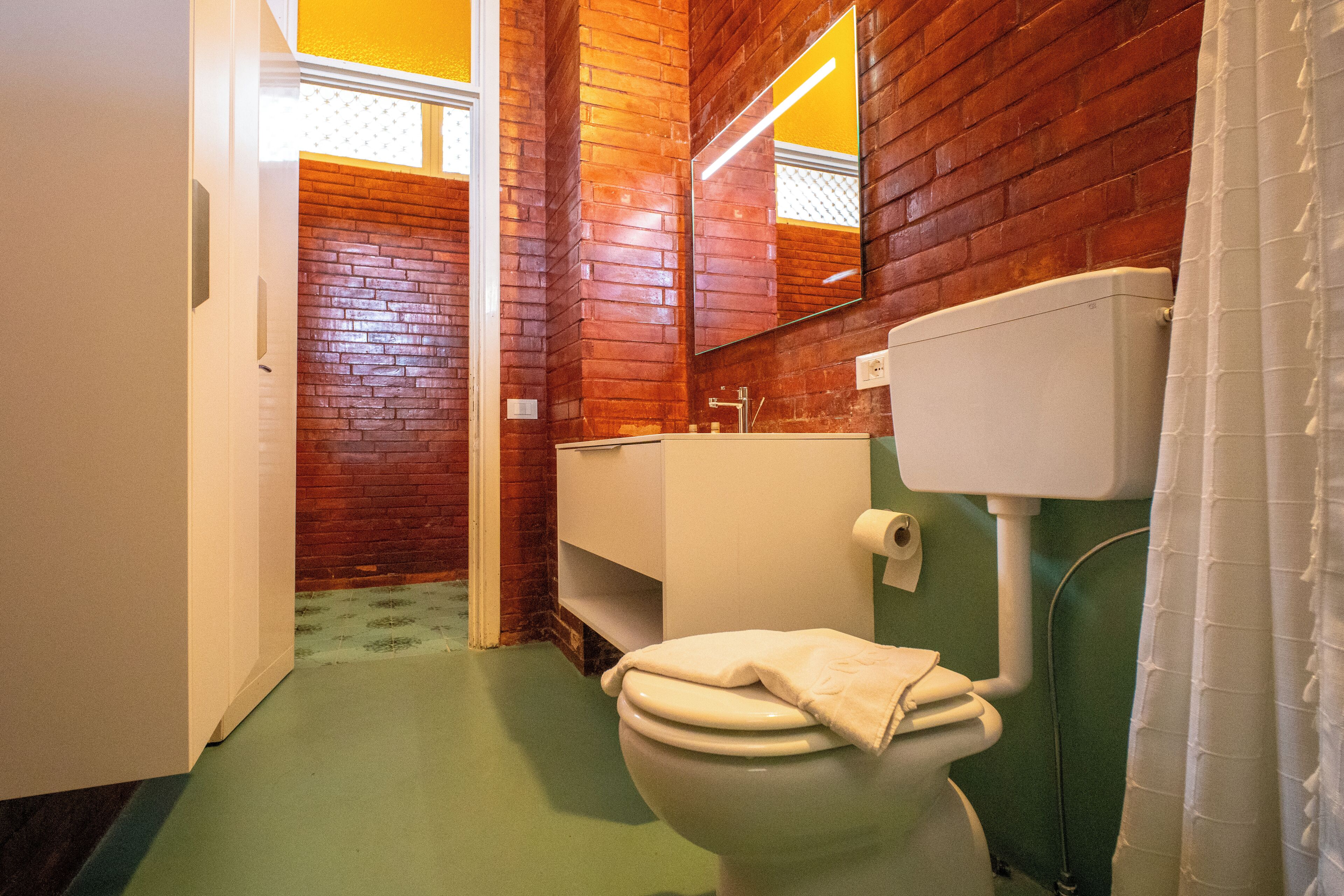 Un bagno con il water, un lavandino e uno specchio.
