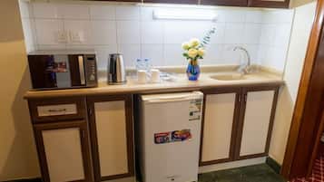 Une cuisine de taille réduite équipée d’un réfrigérateur, d’une machine à café et d’un évier.