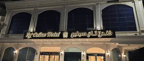 The exterior of Taj Celine Hotel with a grand entrance, two parked SUVs, and a clear view of the entrance doors.